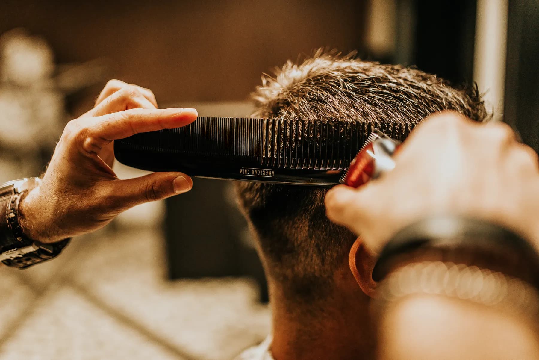 Stylist shaping the back of a short haircut with comb and shears